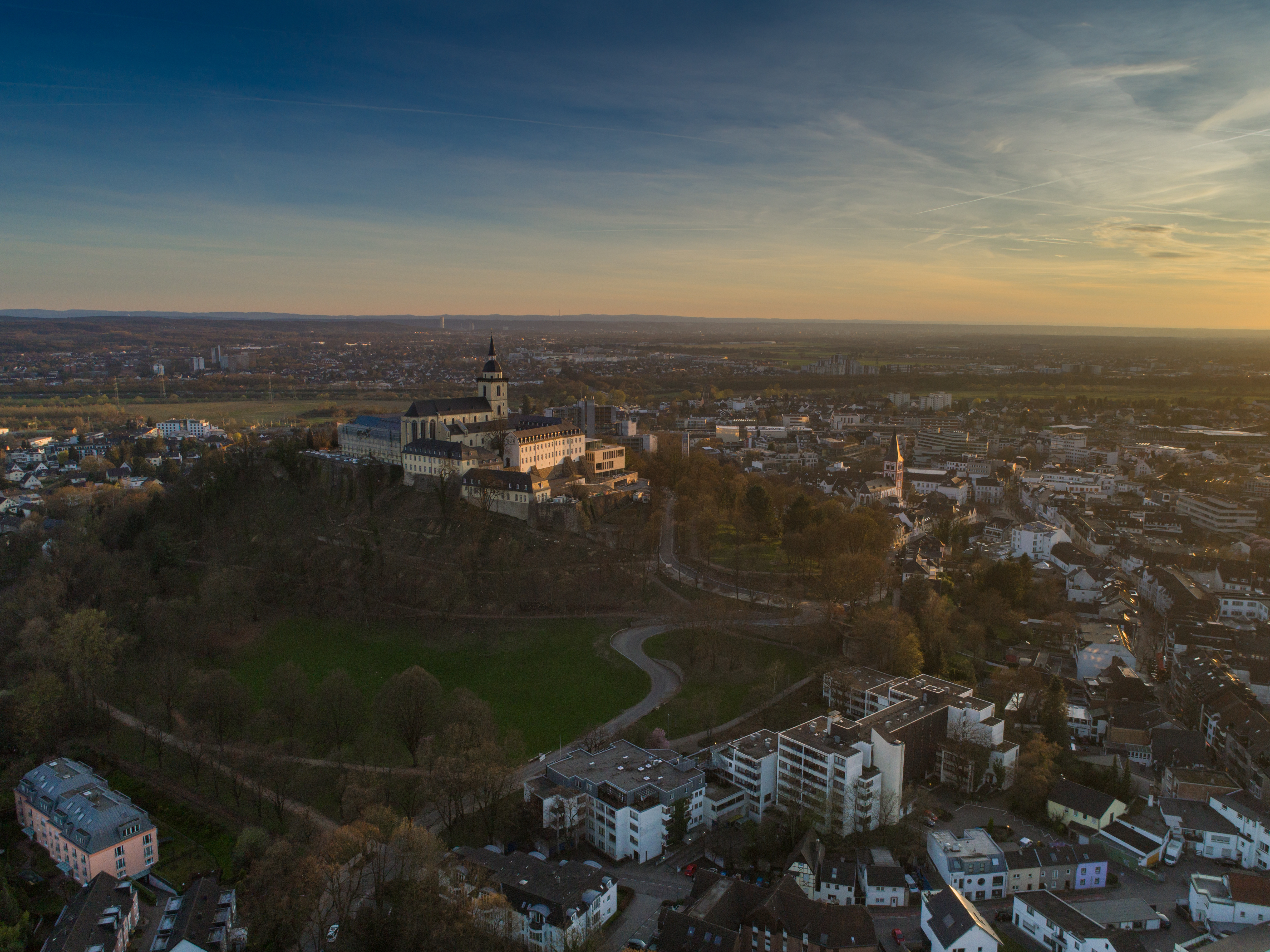 Luftaufnahme einer Stadt mit einem Schloss auf einem Hügel und Wohngebäuden im Vordergrund.