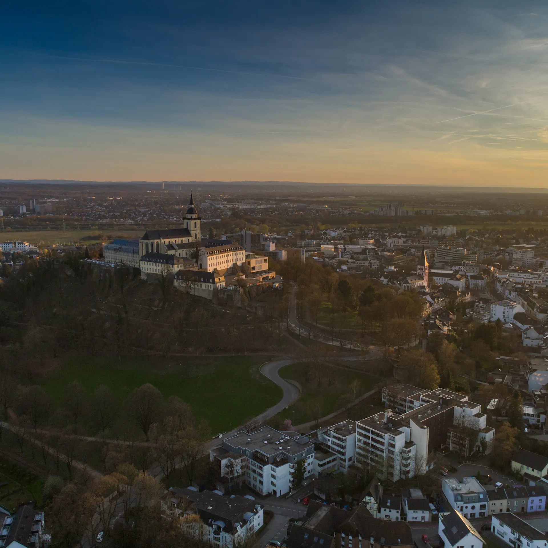 Luftaufnahme einer Stadt mit einem Schloss auf einem Hügel und Wohngebäuden im Vordergrund.