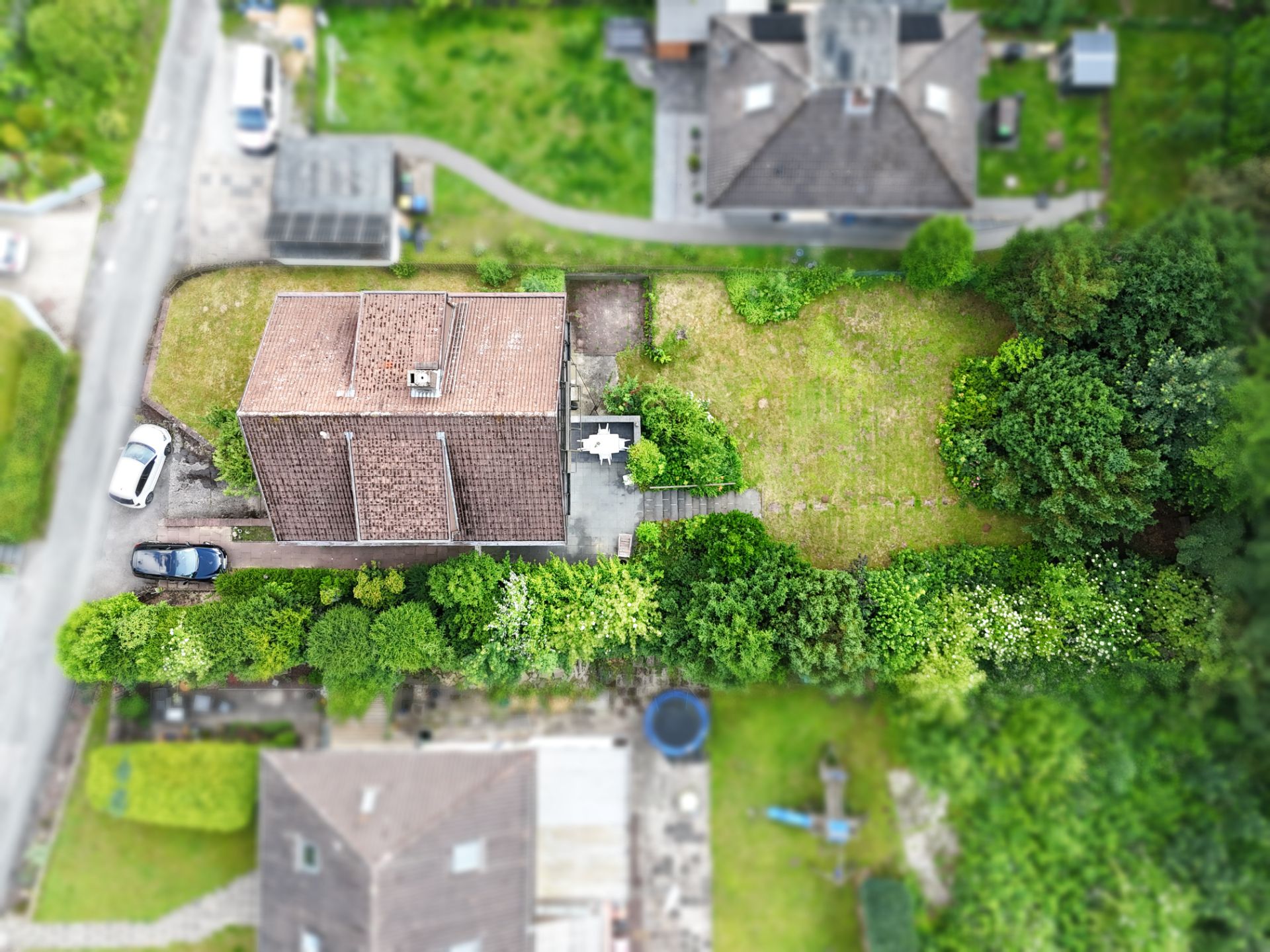 Luftaufnahme eines Hauses mit Garten, Terrasse und umliegendem Grün.