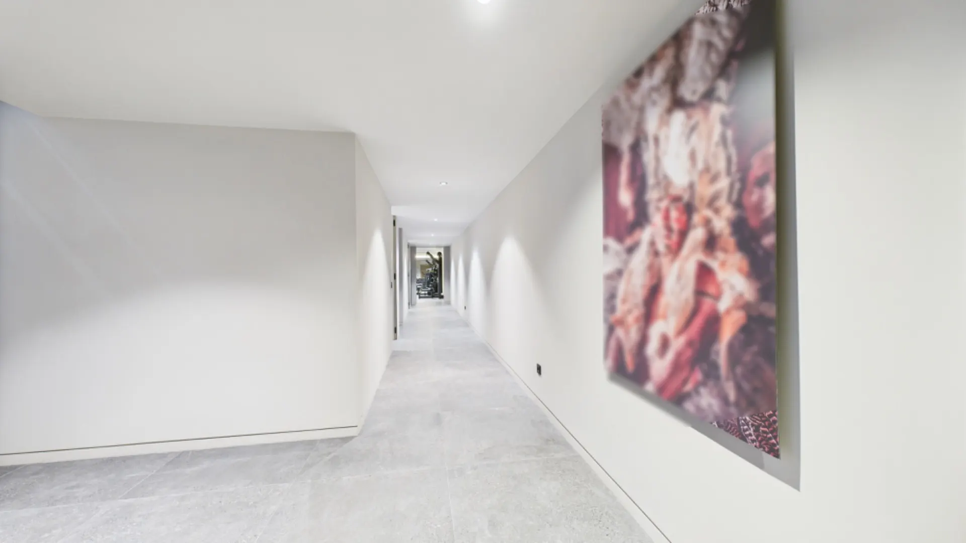 Langer, heller Flur mit Fliesenboden und einem großen Bild an der rechten Wand.