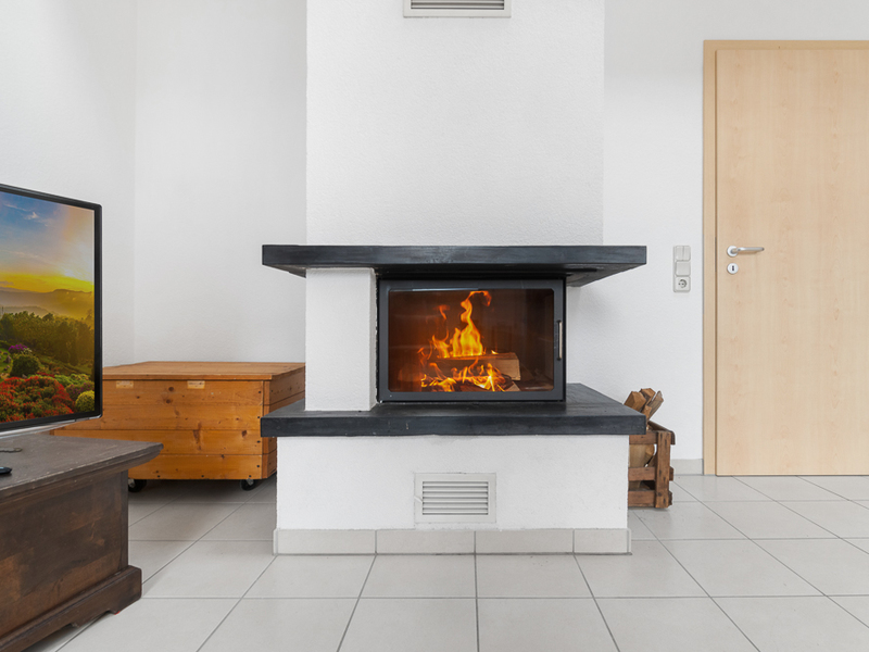 Moderner Kamin mit brennendem Feuer in einem hellen Wohnzimmer mit Fliesenboden.
