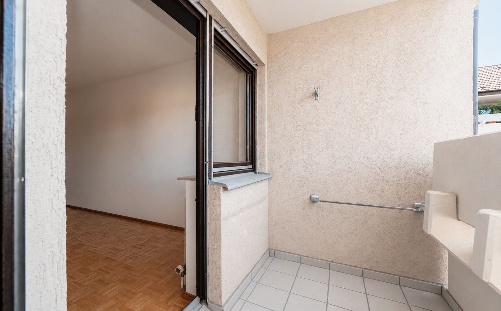 Kleiner Balkon mit Fliesenboden, Zugang zu einem Zimmer mit Parkettboden.