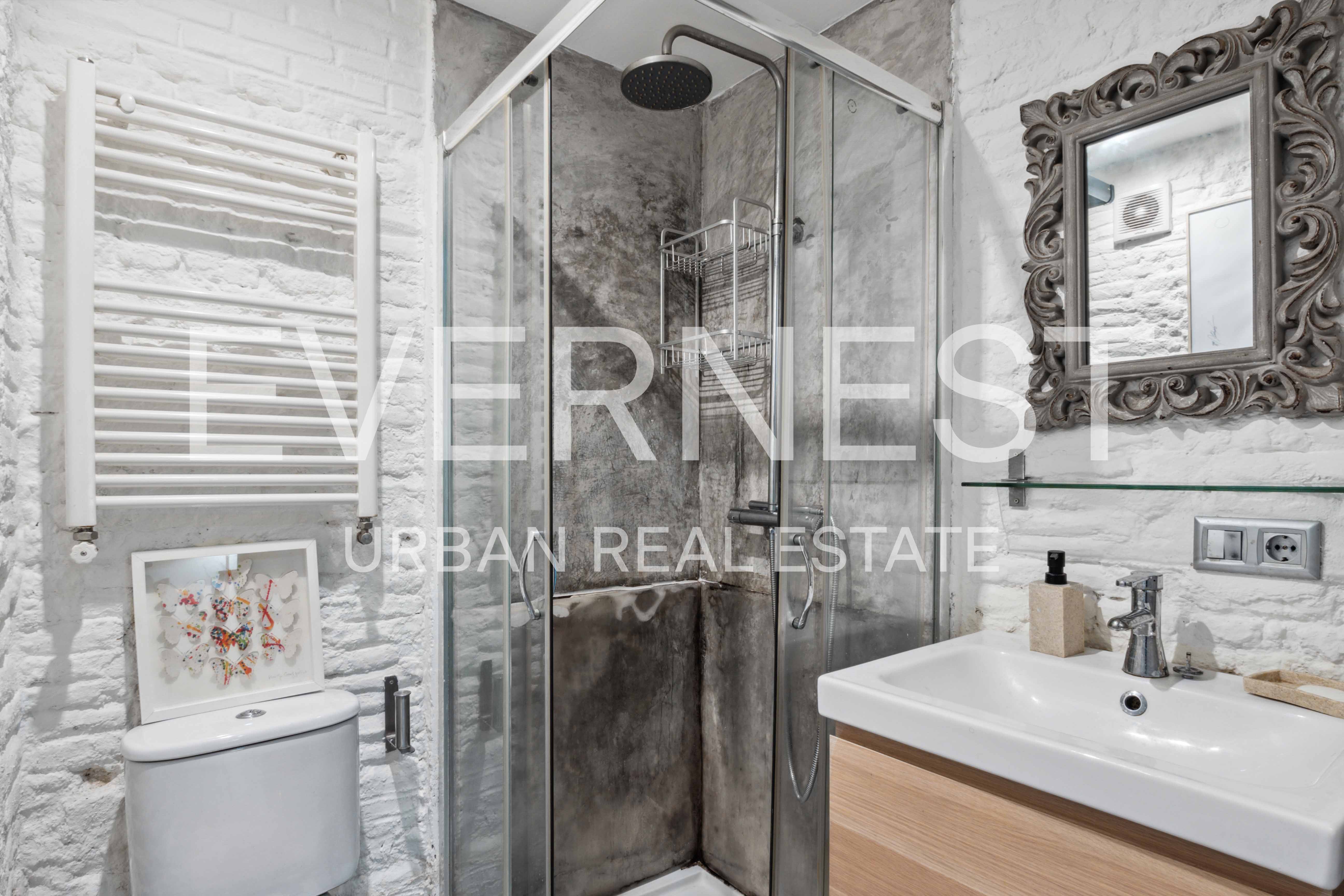Modernes Badezimmer mit Glasdusche, Waschbecken, Spiegel und Heizkörper an weißer Backsteinwand.