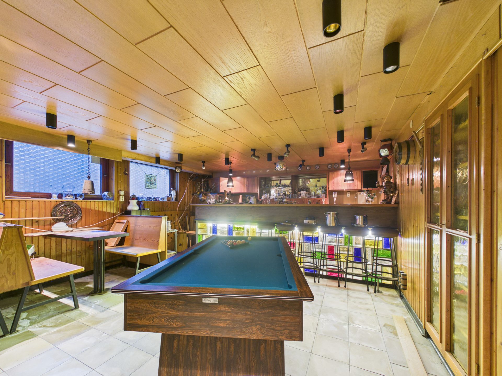 Kellerraum mit Billardtisch, Bar, Sitzbänken und Holzvertäfelung.