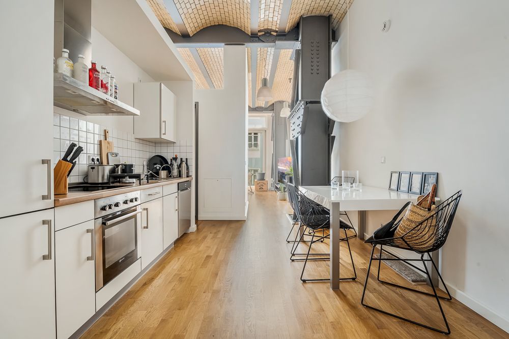Moderne Küche mit weißen Schränken, Esstisch und zwei Stühlen auf Holzfußboden.