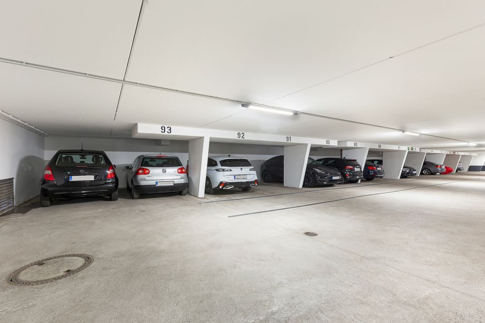 Mehrere Autos parken in nummerierten Stellplätzen in einer hellen Tiefgarage.