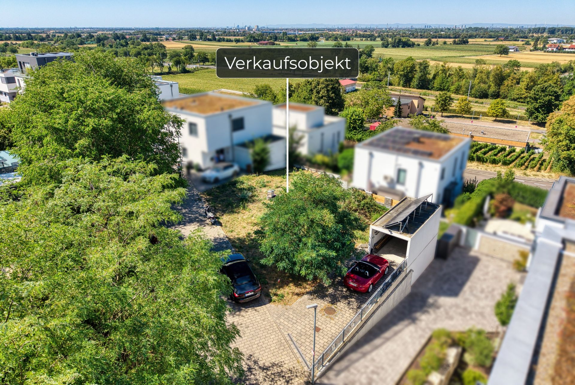 Luftaufnahme eines Grundstücks mit Bäumen, zwei parkenden Autos und modernen Wohnhäusern.