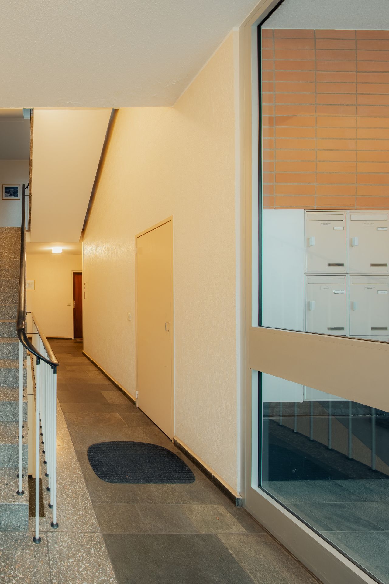 Helle Hausflur mit Treppe, Briefkästen und Teppichläufer.