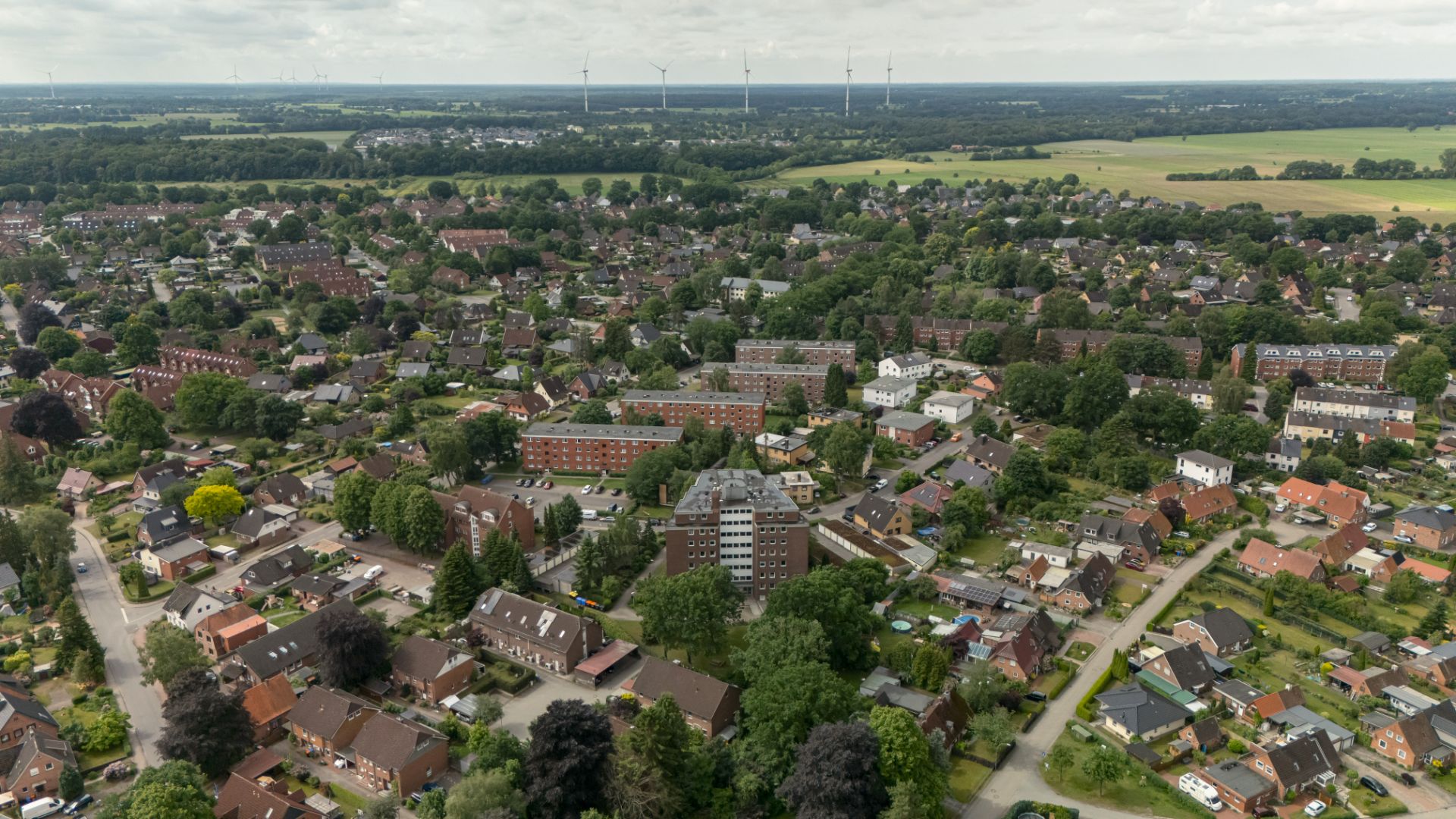 Luftaufnahme eines Wohngebiets mit vielen Häusern, Bäumen und Straßen.
