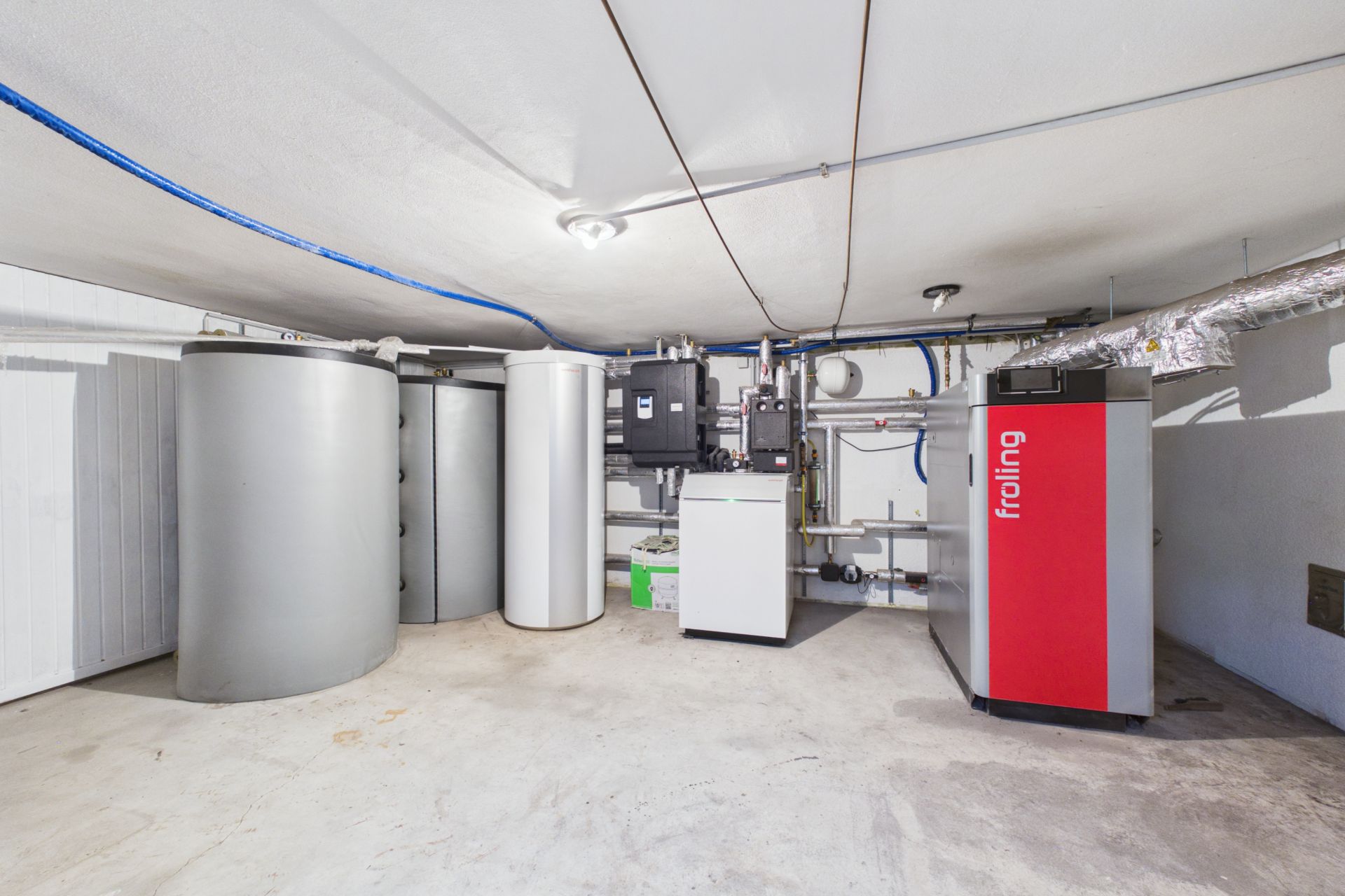 Kellerraum mit mehreren Heizungsanlagen und großen silbernen Tanks.