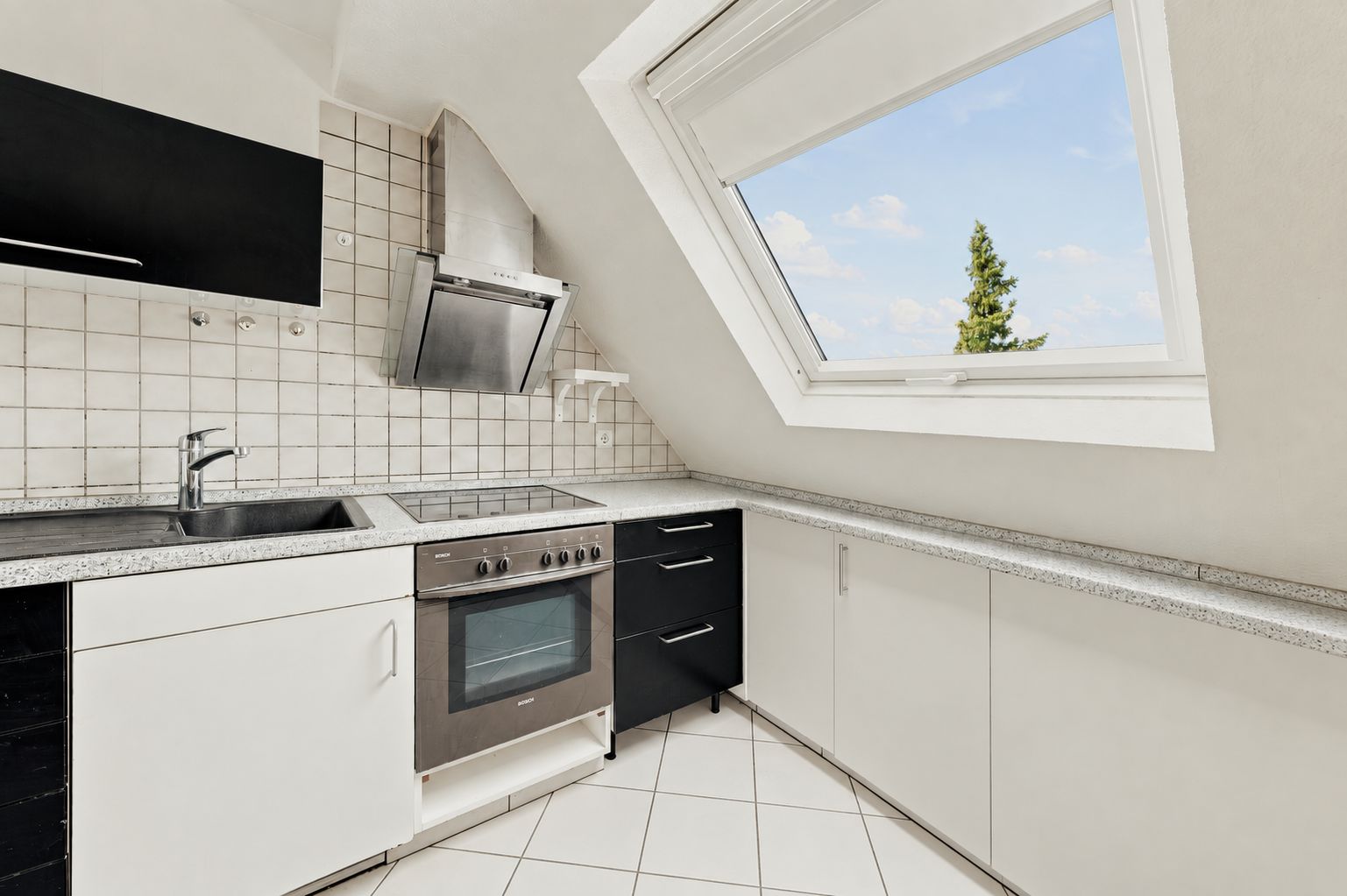 Moderne Dachgeschossküche mit Einbaubackofen, Kochfeld, Spüle und großem Fenster mit Ausblick.