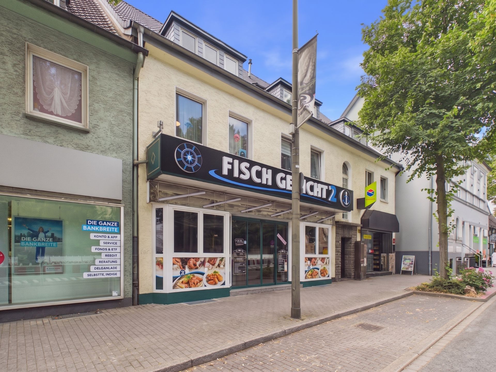 Ladengebäude mit Fischrestaurant im Erdgeschoss und Wohnungen im Obergeschoss an einer Straße.