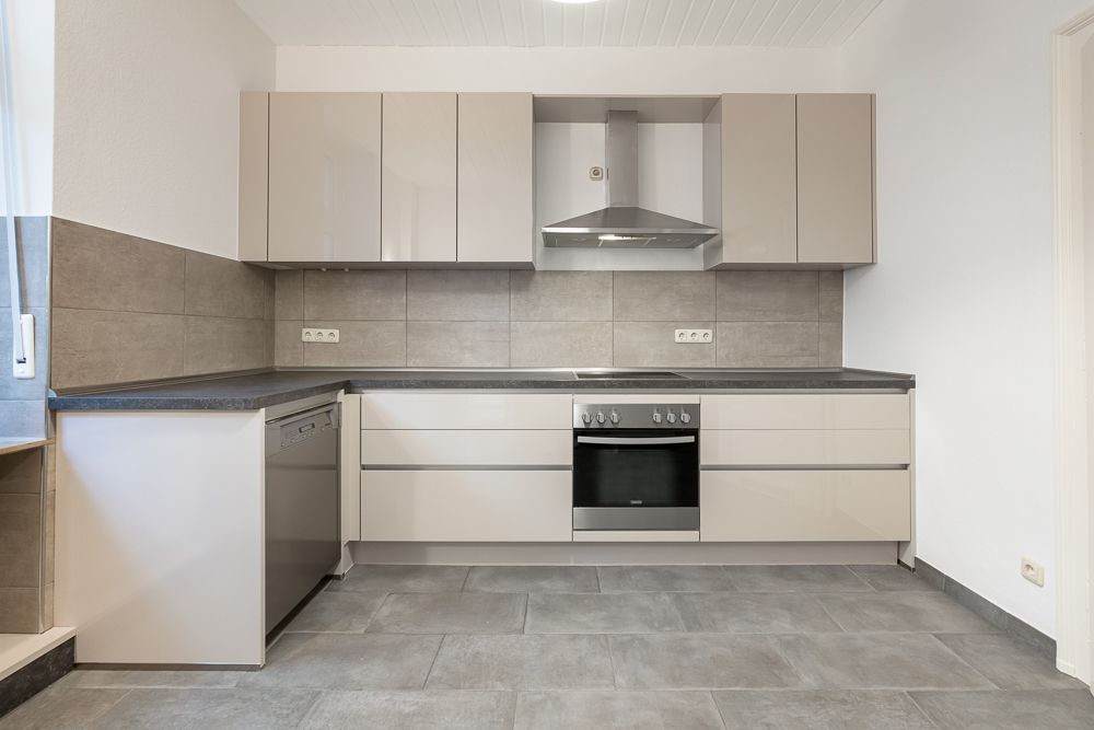 Moderne Einbauküche mit grauen Schränken, Herd, Backofen und Spülmaschine.