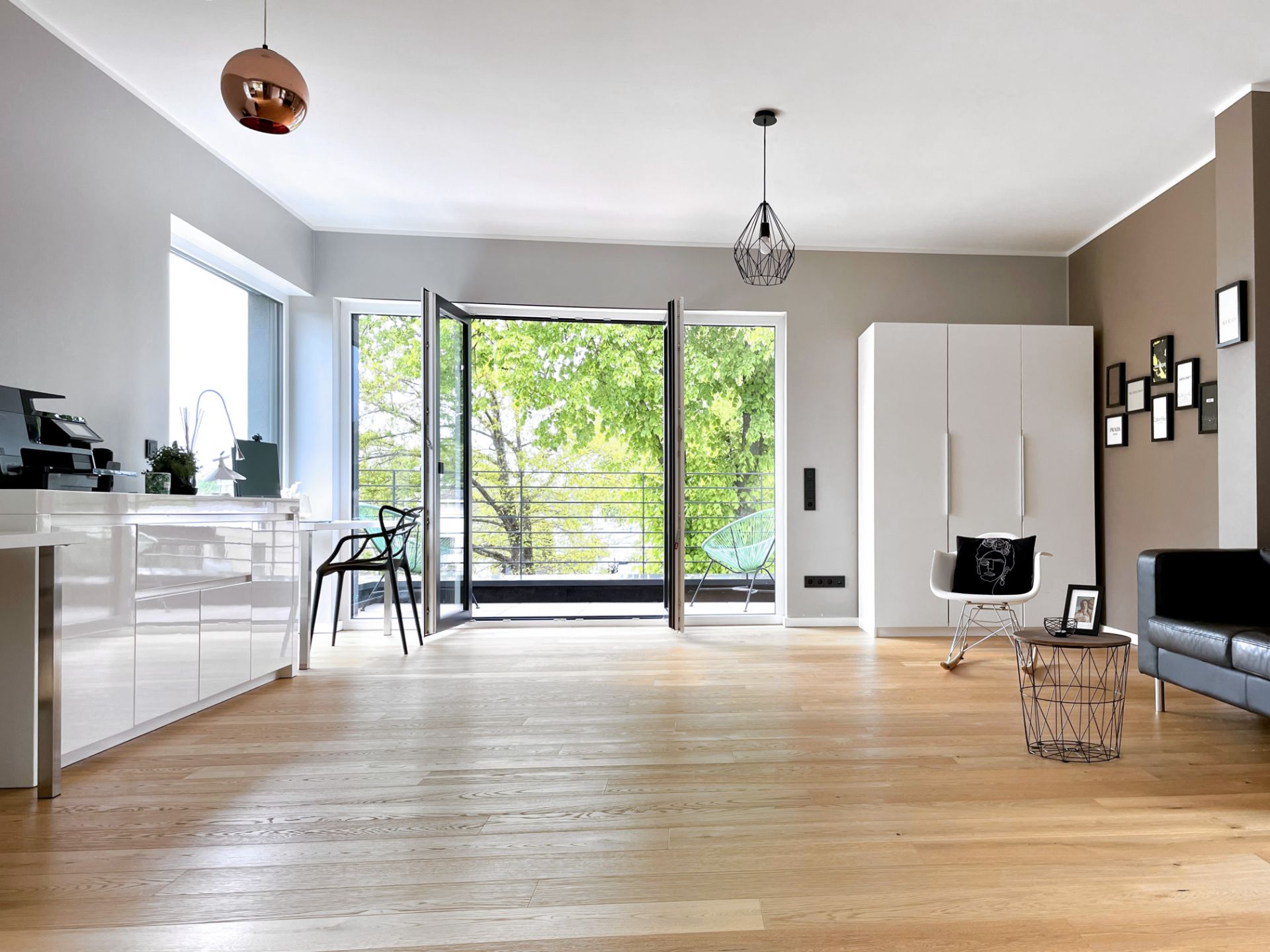 Helles Wohnzimmer mit Holzboden, großen Fenstern und modernen Möbeln, geöffnet zur Terrasse.