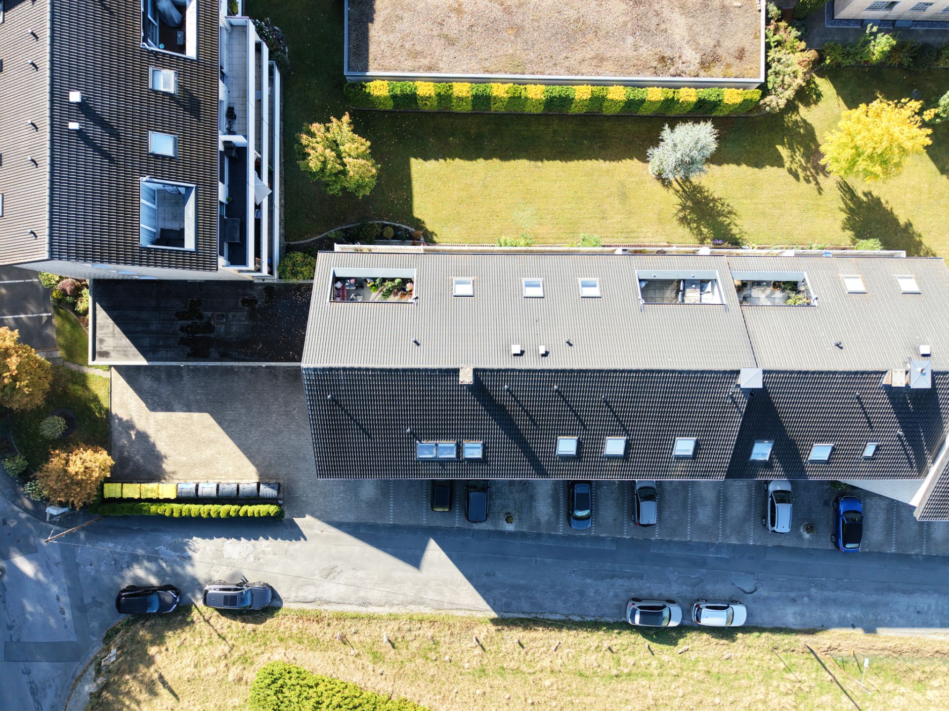 Luftaufnahme eines Wohngebäudes mit angrenzendem Parkplatz und Garten.