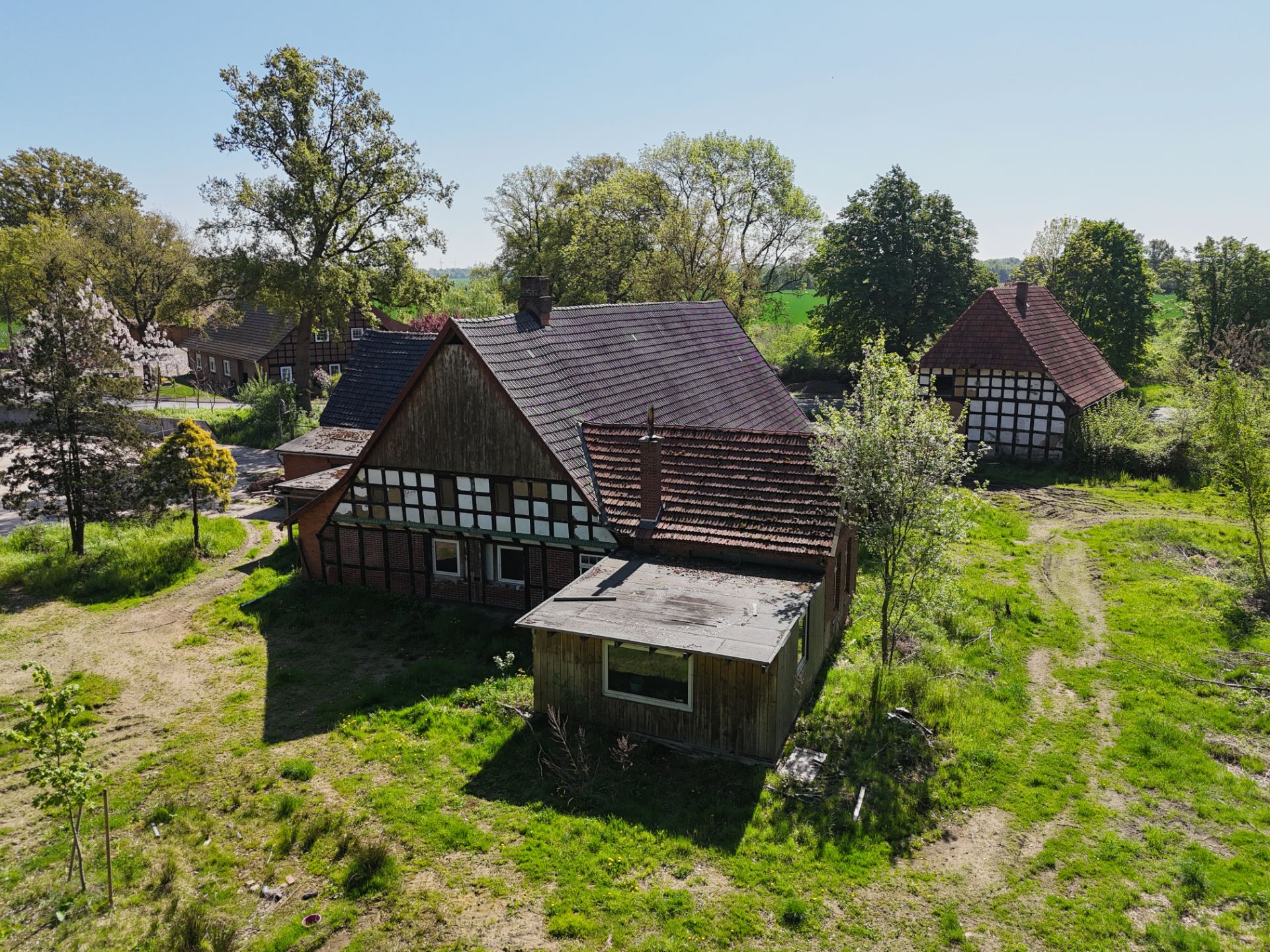 Fachwerkhaus mit Nebengebäuden und grünem Garten bei sonnigem Wetter.