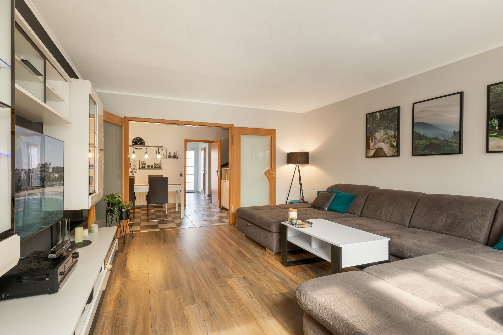 Wohnzimmer mit großer Eckcouch, Couchtisch, TV und Blick in Essbereich mit Tisch und Stuhl.