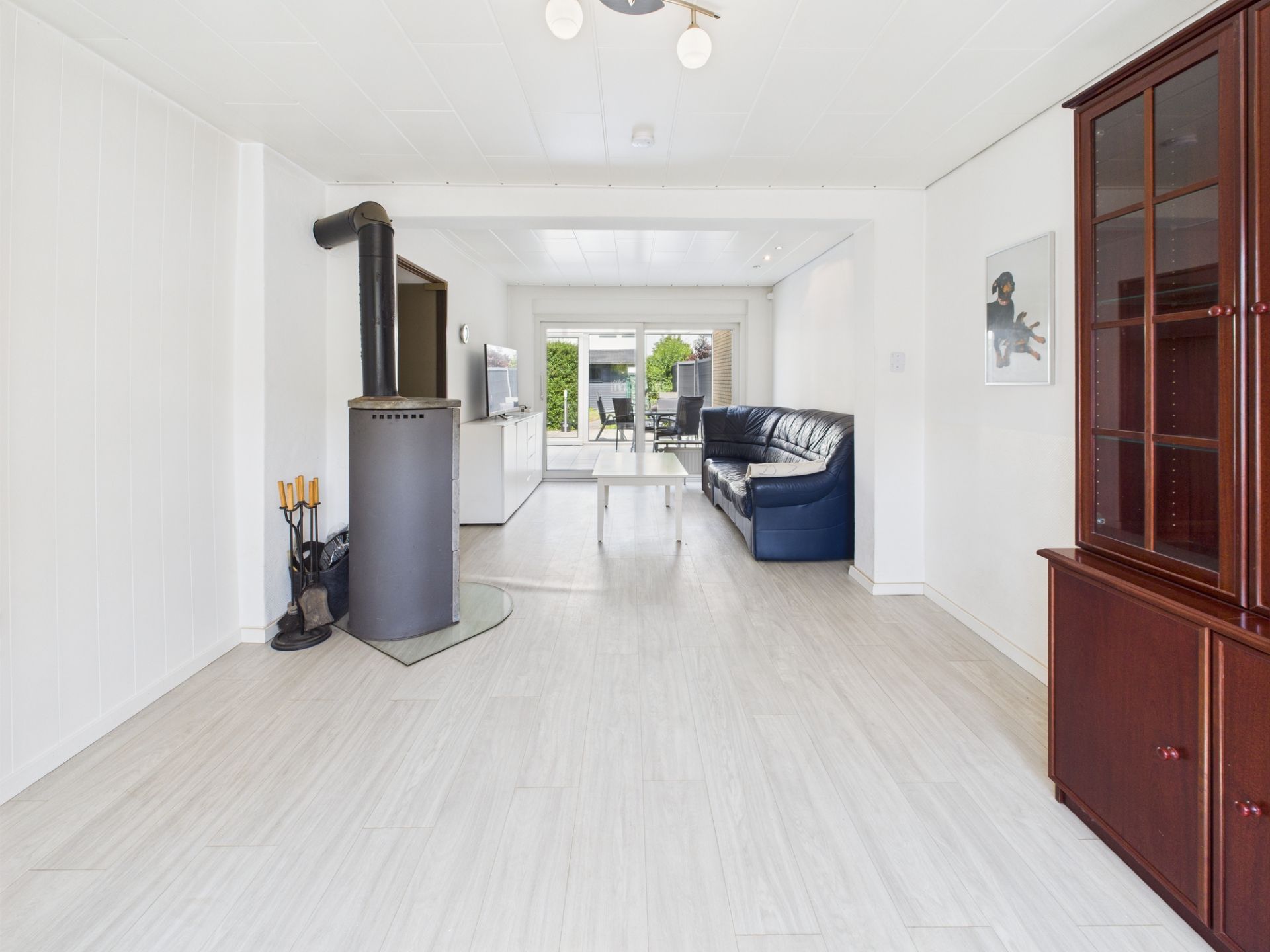Helles Wohnzimmer mit Kamin, dunkelblauem Sofa und Glastür zum Garten.
