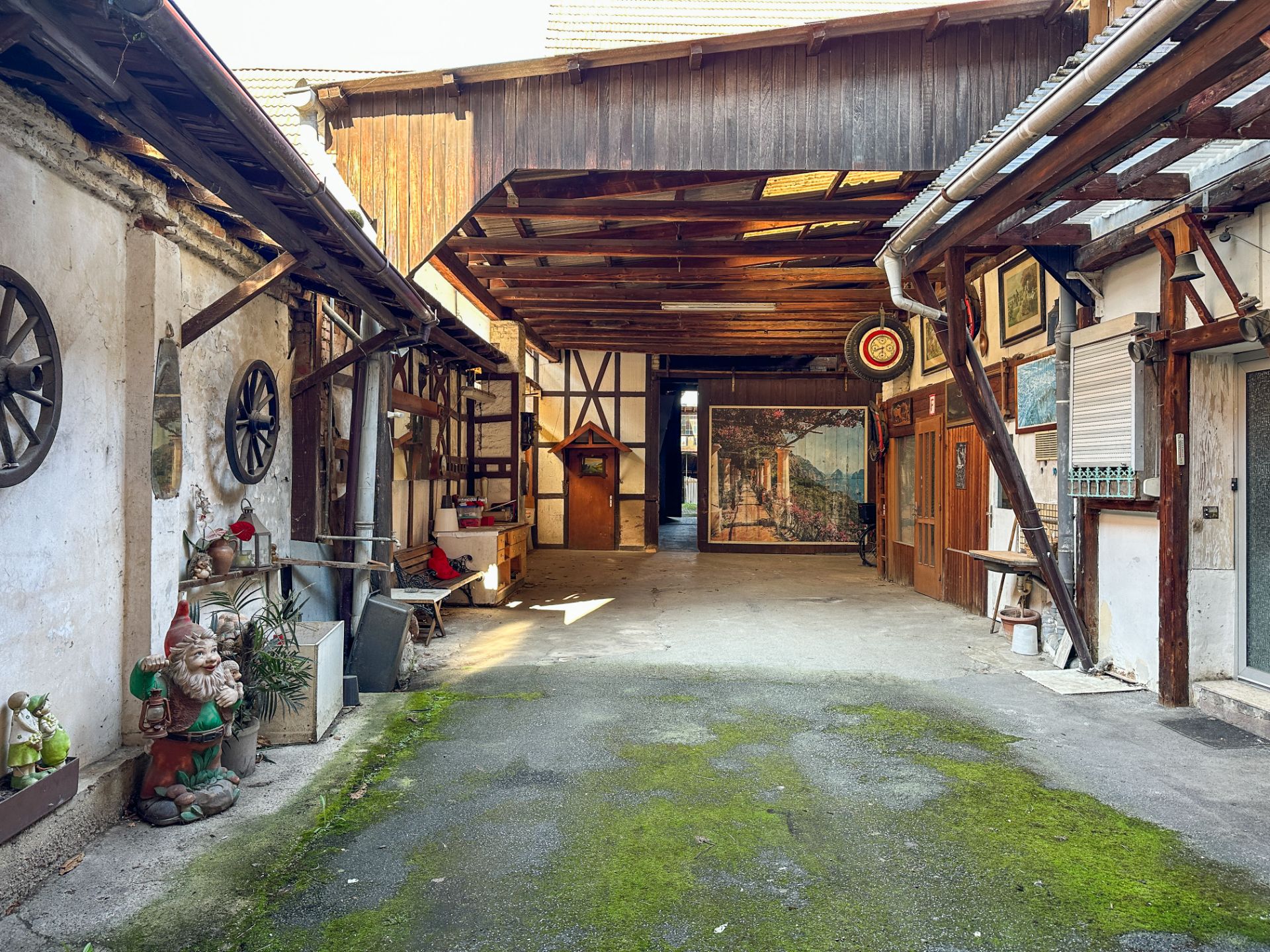 Überdachter Innenhof mit Fachwerk, Gartenzwergen und Wanddekorationen.