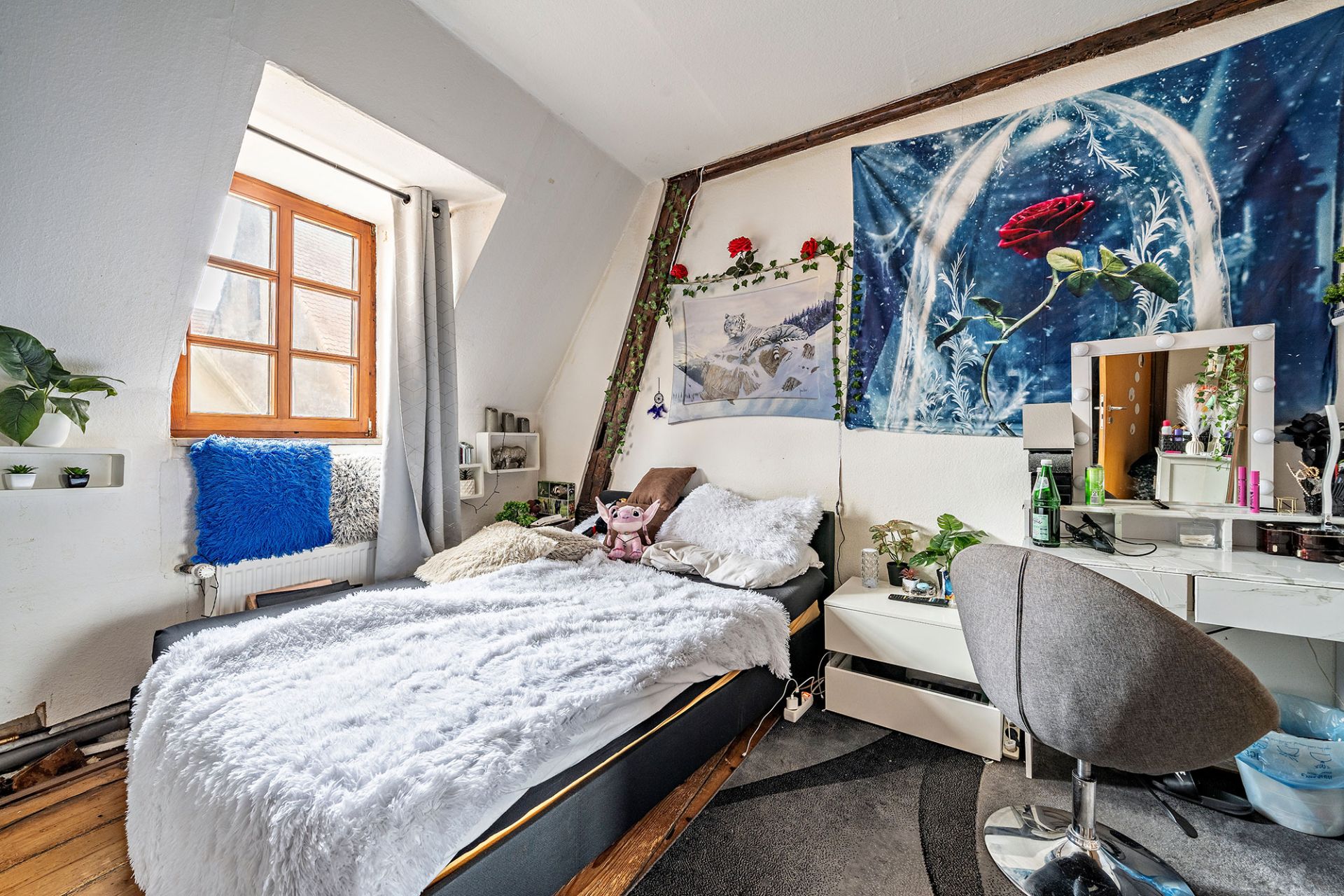 Gemütliches Schlafzimmer mit Bett, Spiegelkommode, Pflanzen und Wanddekorationen.