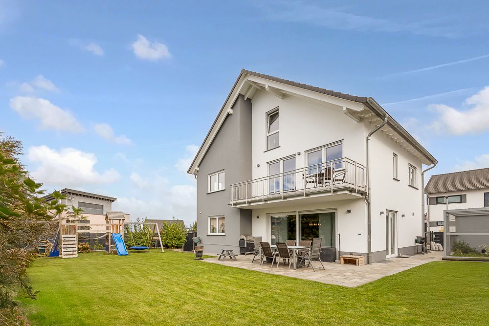 Modernes Einfamilienhaus mit Balkon, Terrasse und großem Garten mit Kinderspielplatz.
