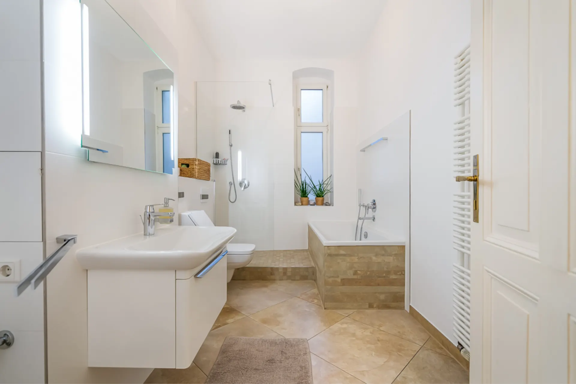 Modernes Badezimmer mit Dusche, Badewanne, Waschbecken und zwei Fenstern, Pflanzen auf dem Fenstersims.