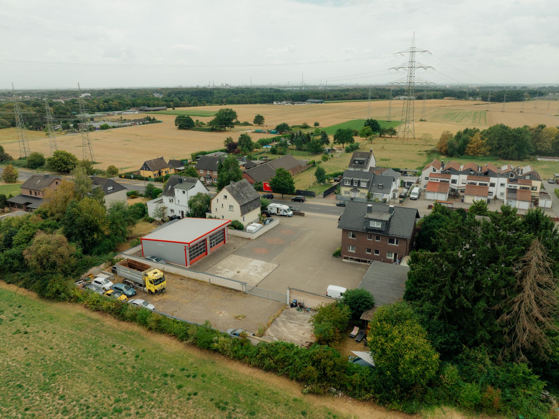 Luftaufnahme von Wohnhäusern, Feldern und einem Gebäude mit mehreren Garagentoren.