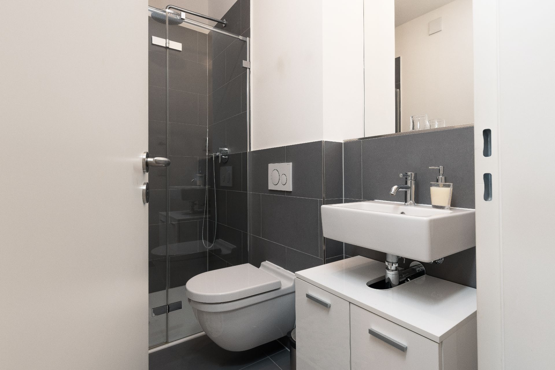 Modernes Badezimmer mit Dusche, Hänge-WC und Waschbecken mit Spiegelschrank.