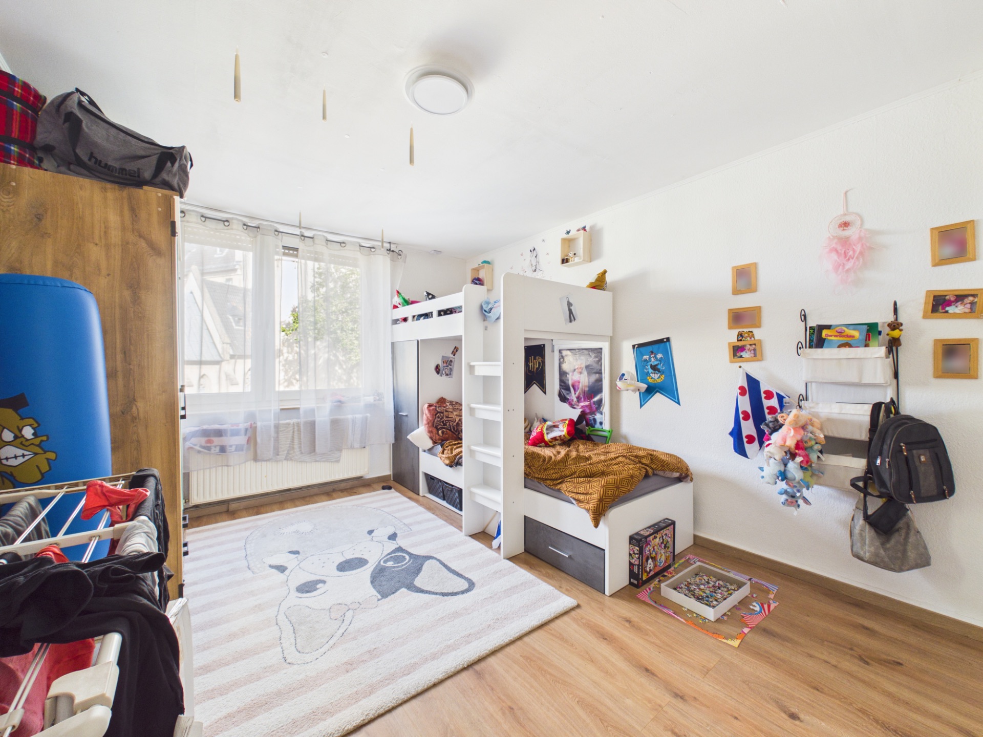 Helles Kinderzimmer mit Etagenbett, Teppich, Spielzeug und Wanddekoration.