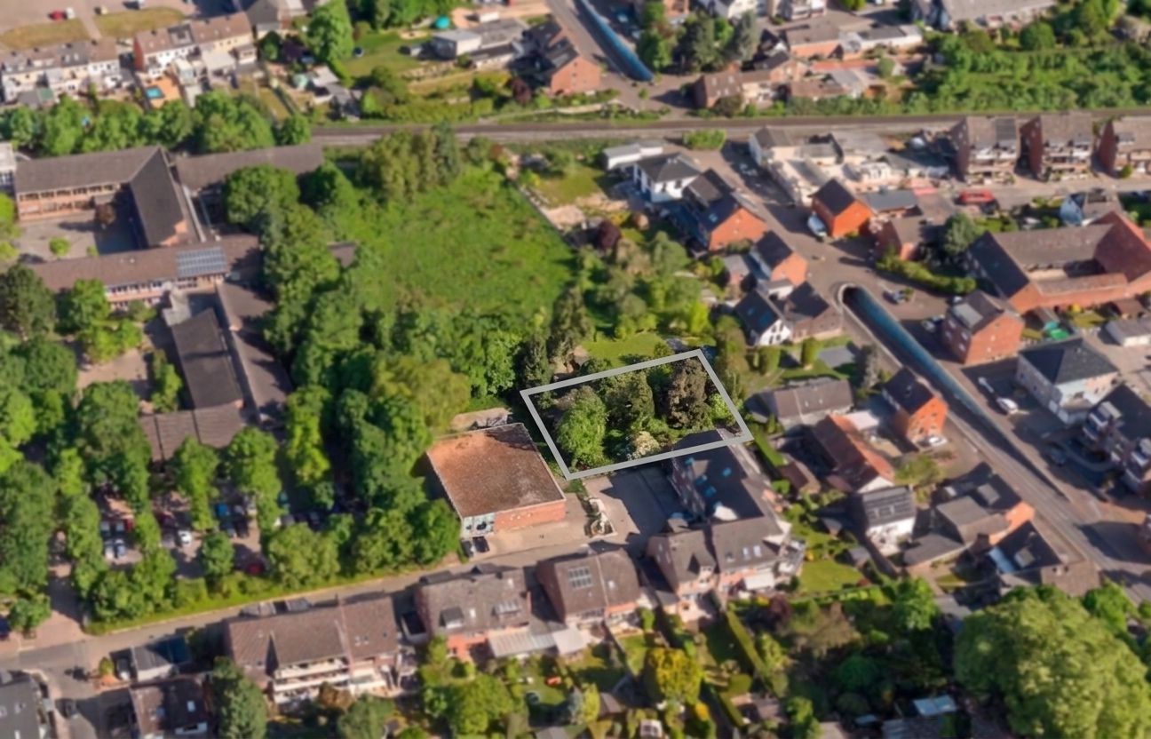 Luftbild einer Wohngegend mit markiertem Grundstück, umgeben von Häusern und Bäumen.