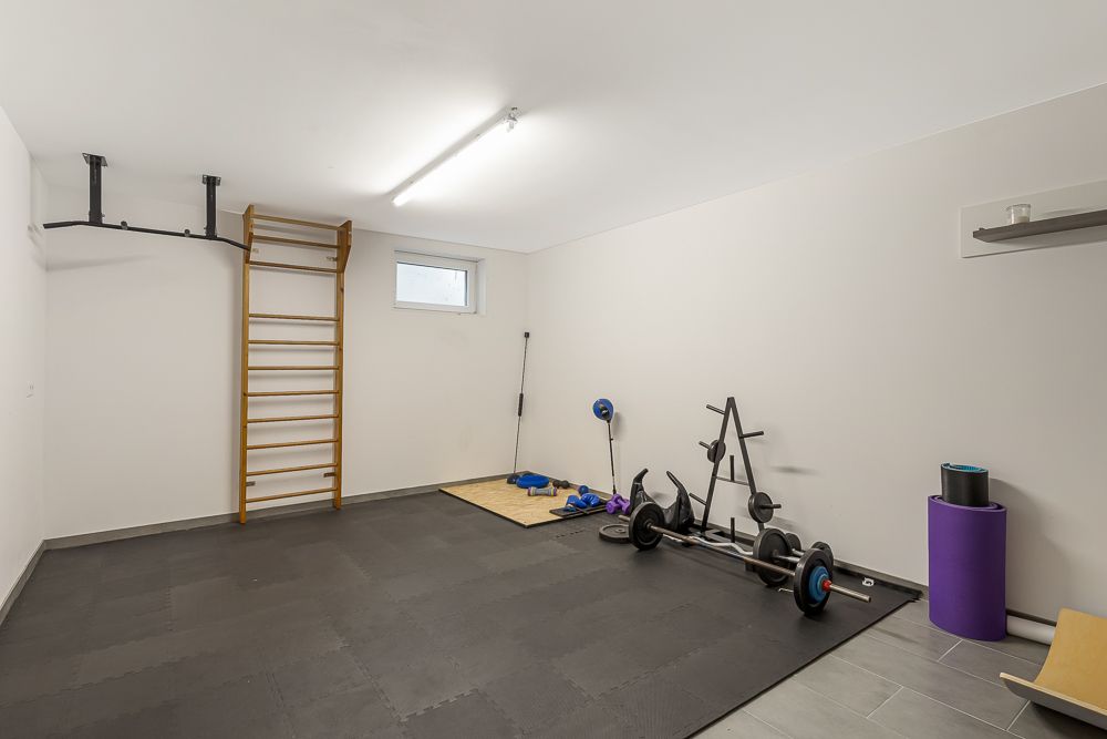 Heller Fitnessraum mit Sprossenwand, Hantelbank, Gymnastikmatten und Trainingsgeräten.