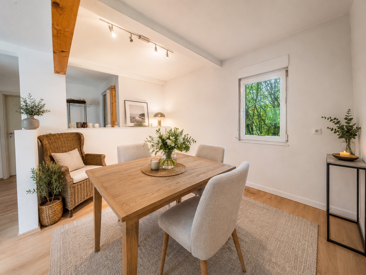 Essbereich mit Holztisch, vier Stühlen, Fenster und Sessel, dekoriert mit Pflanzen.