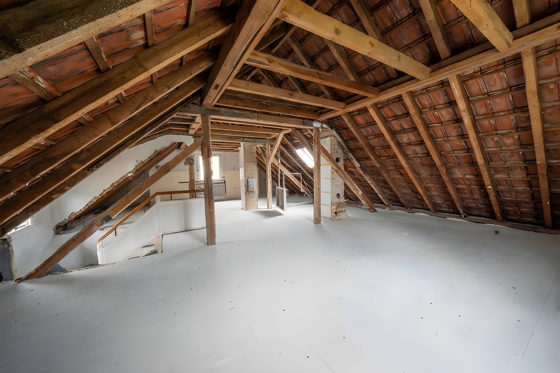 Dachboden mit sichtbaren Holzbalken, Schrägdach und hellem Boden.
