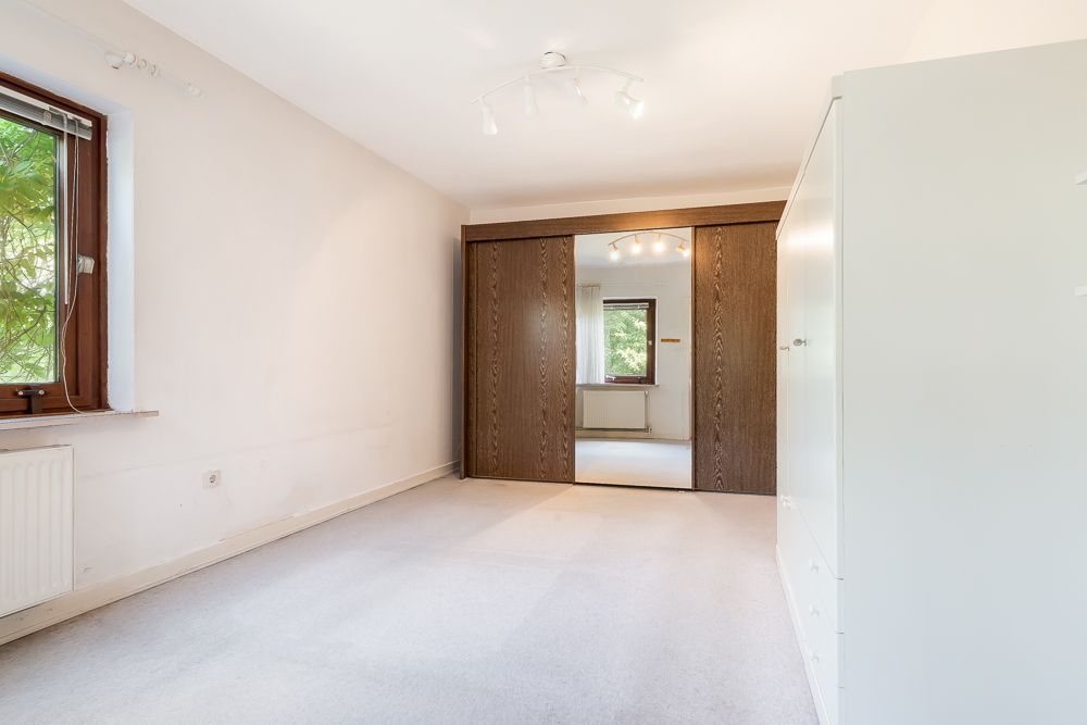 Helles, leeres Zimmer mit großem Spiegel-Schrank, Fenster und weißem Schrank.