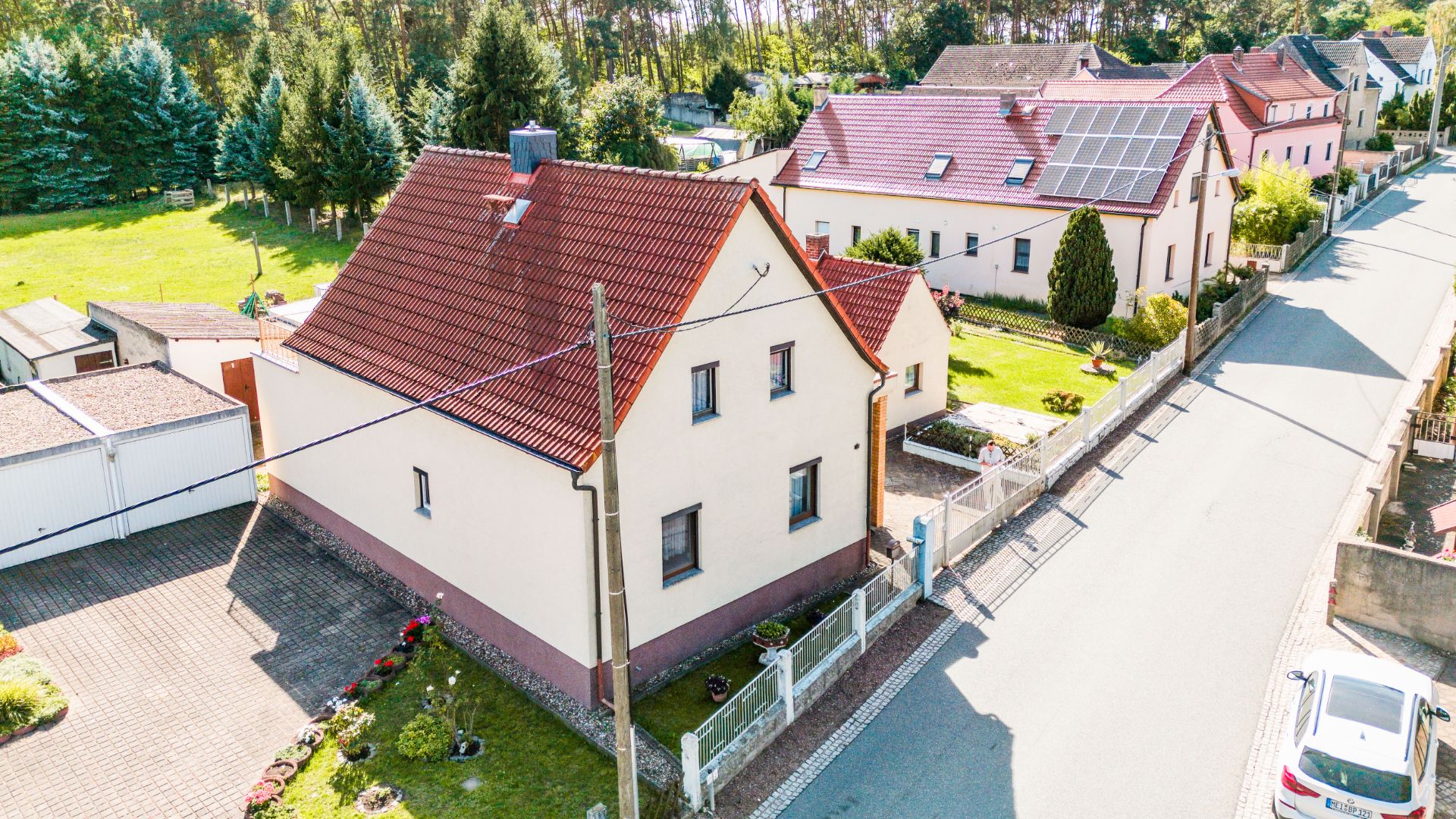 Zweistöckiges Wohnhaus mit rotem Dach und Vorgarten an einer ruhigen Straße.