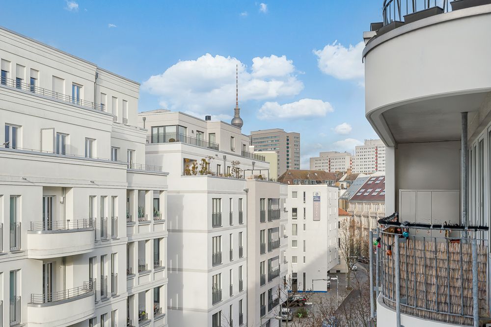 Blick von einem Balkon auf moderne Wohngebäude in einer Stadt bei blauem Himmel.