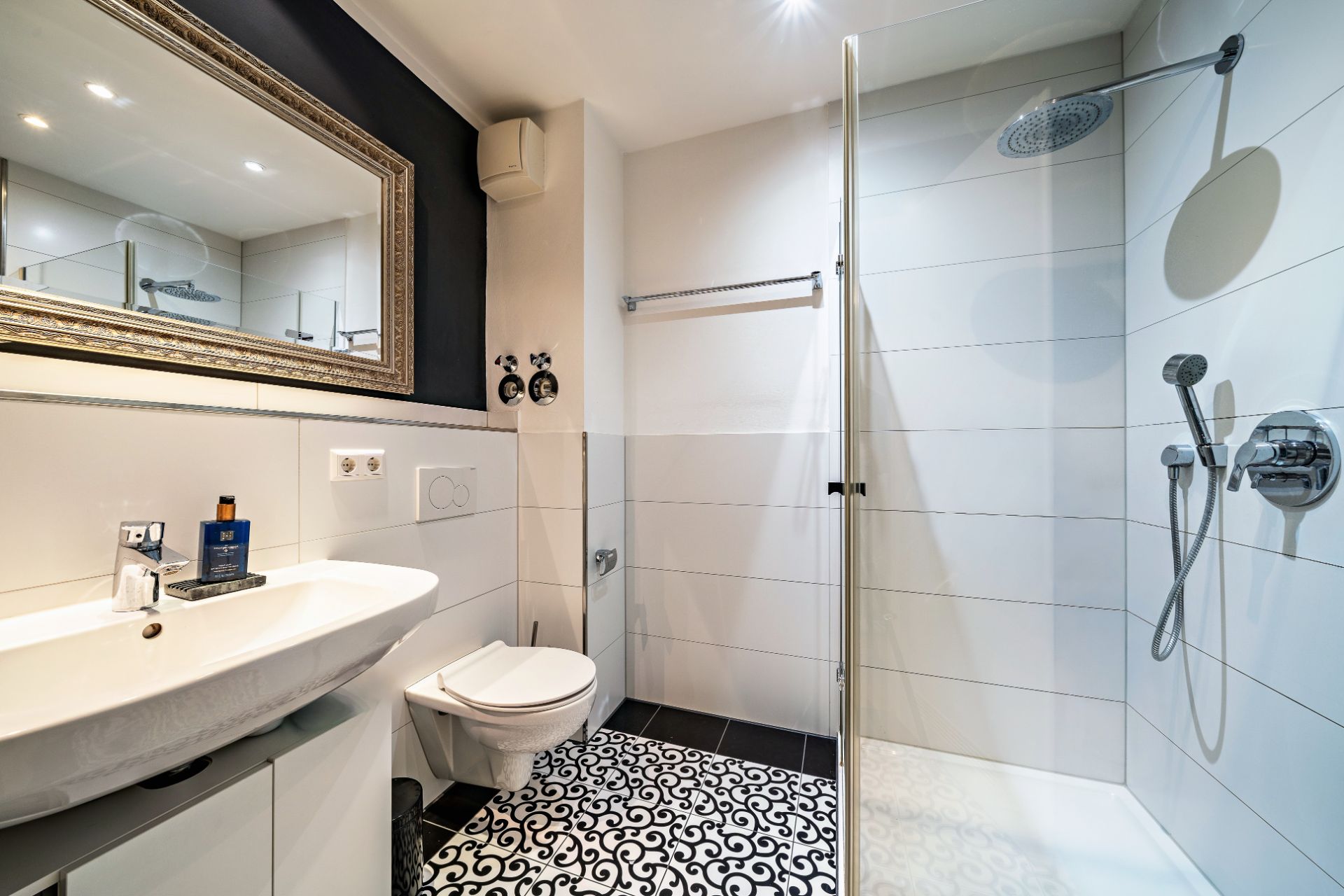 Modernes Badezimmer mit großem Spiegel, Waschbecken, WC und begehbarer Dusche.