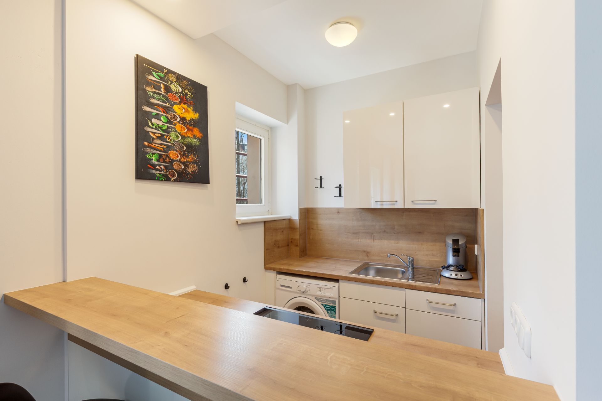 Moderne kleine Küche mit Holzarbeitsplatte, weißem Schrank und einem Bild an der Wand.