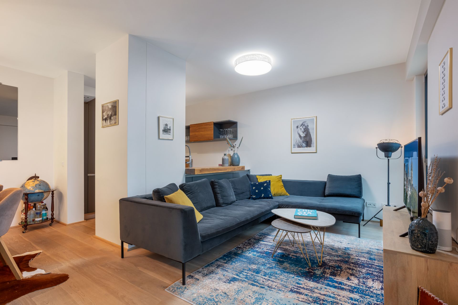 Modernes Wohnzimmer mit dunklem Ecksofa, Couchtisch, Teppich und Wandbildern.