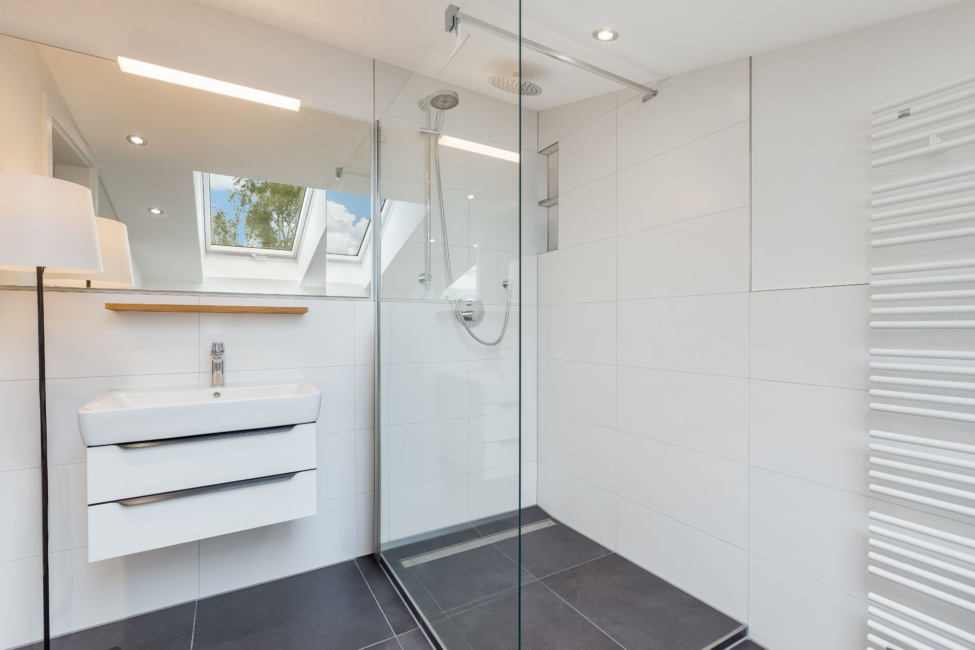 Modernes Badezimmer mit begehbarer Dusche, Waschbecken, Spiegel und Dachfenstern.