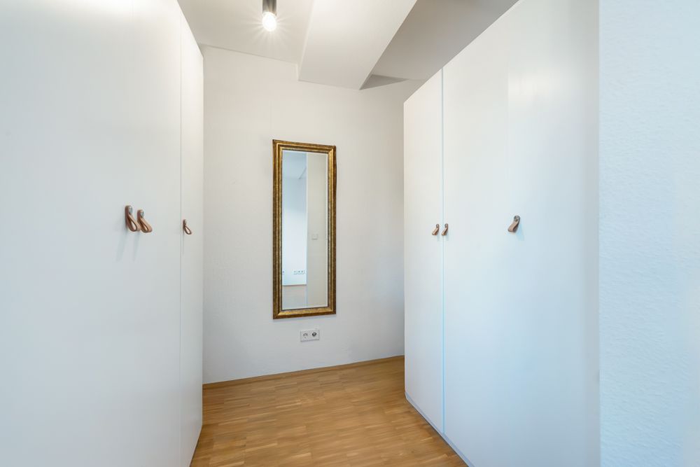 Heller Flur mit zwei weißen Schränken und einem großen Spiegel an der Wand.