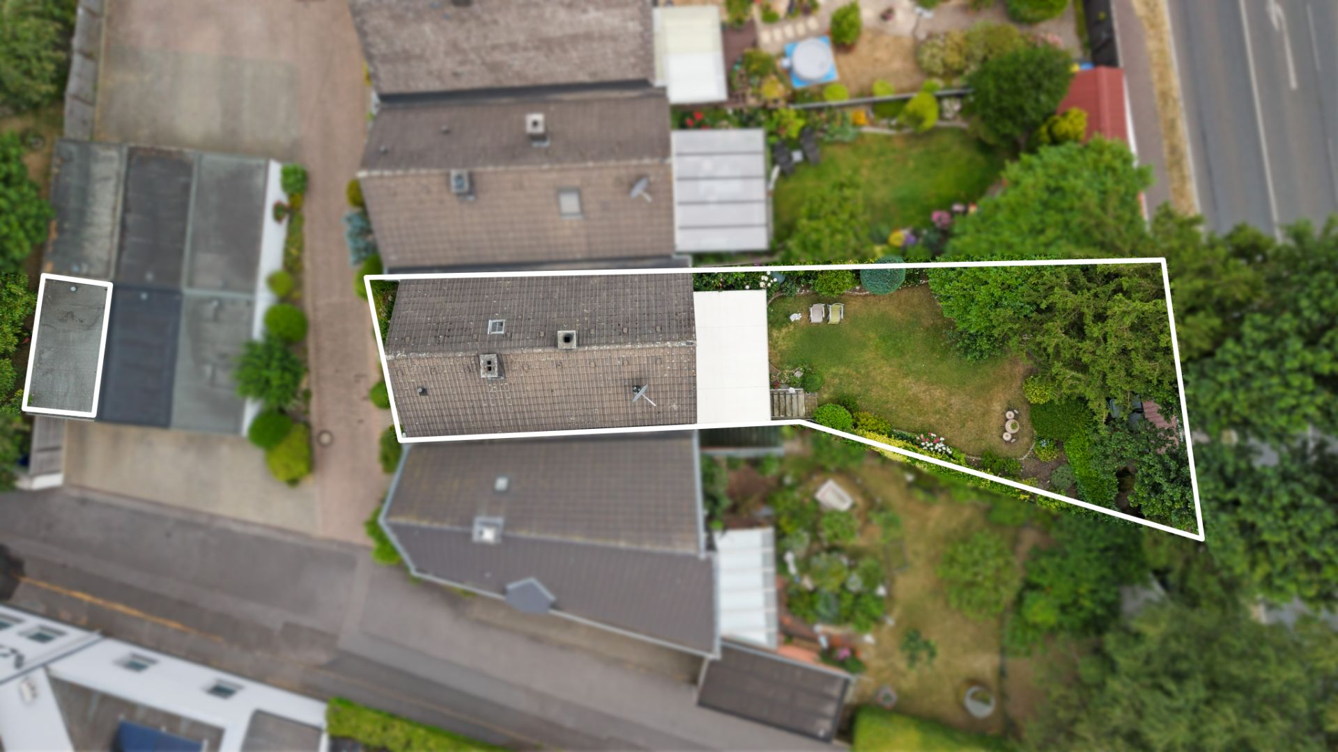 Luftaufnahme eines Wohnhauses mit Garten, Grundstück ist weiß umrandet.