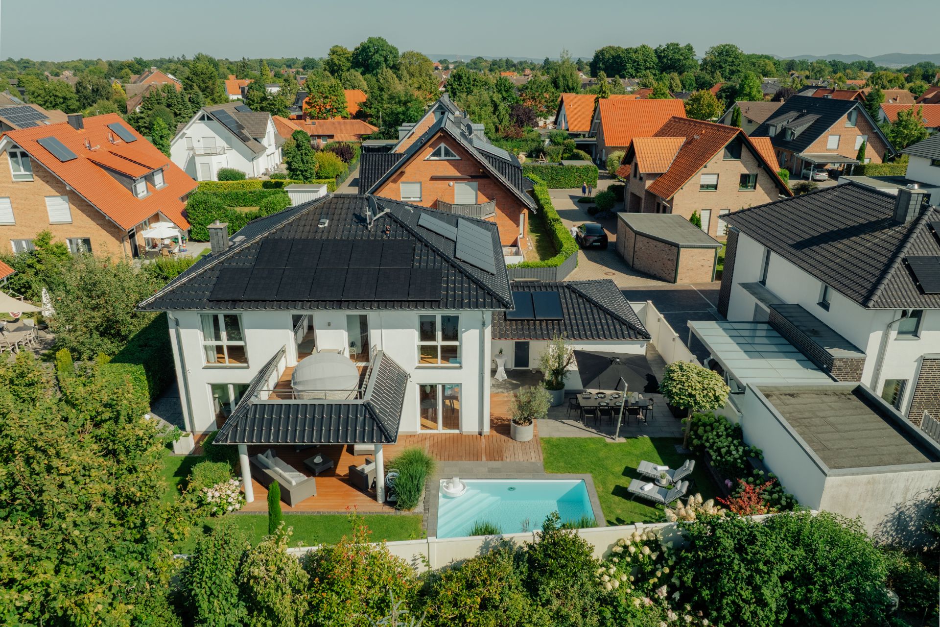 Modernes Einfamilienhaus mit Garten, Terrasse und kleinem Pool in einem Wohngebiet.