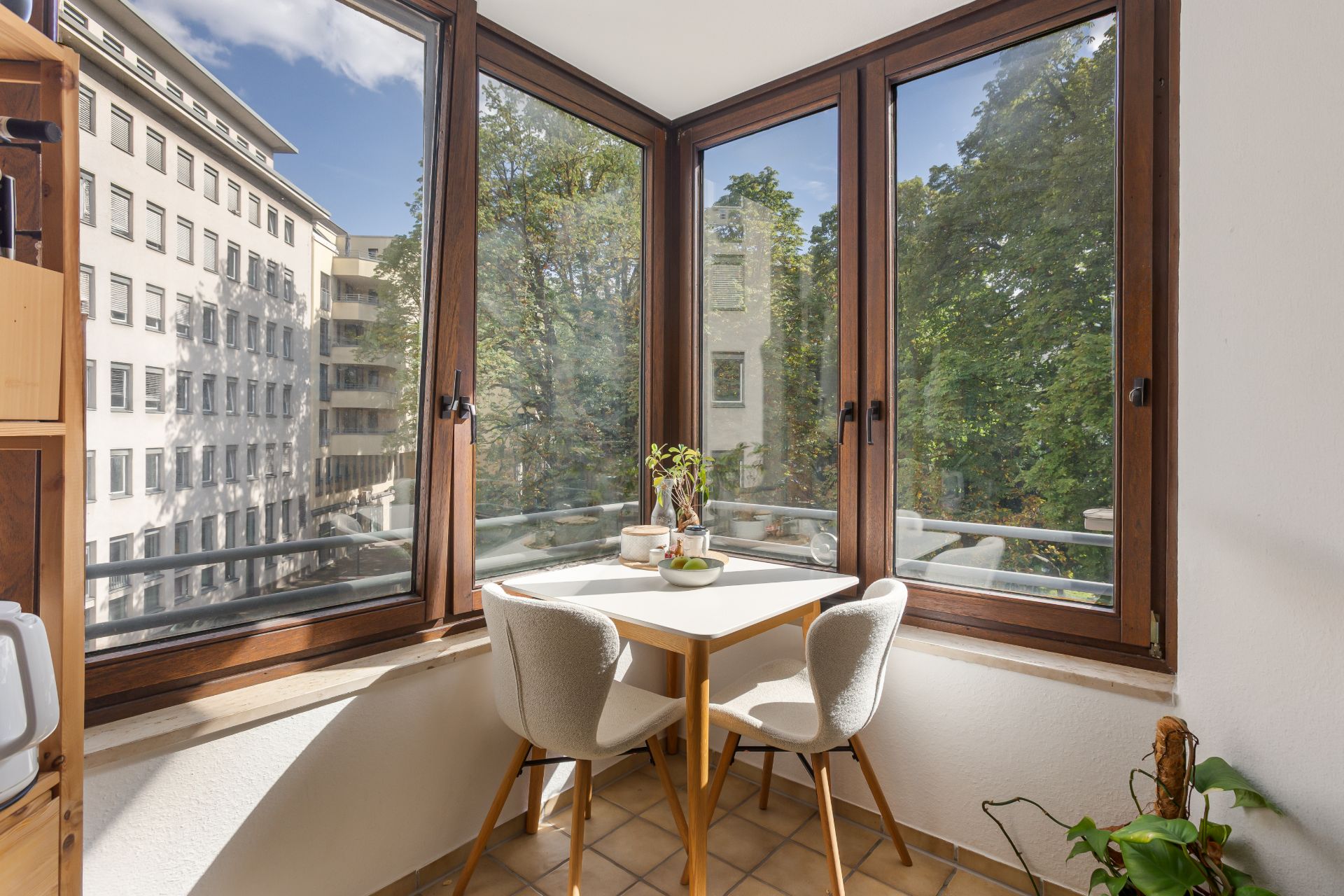 Kleiner Essbereich mit zwei Stühlen an einem Tisch vor großen Fenstern mit Blick ins Grüne.