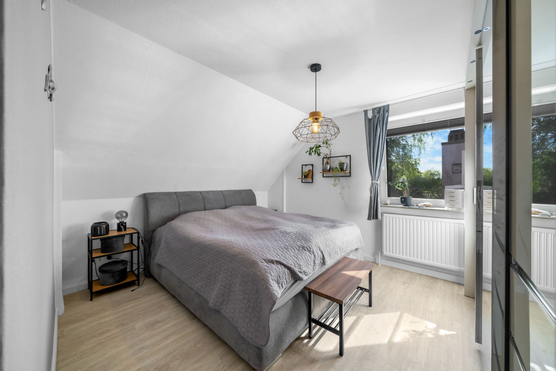 Helles Schlafzimmer mit Doppelbett, Nachttisch, Fenster und modernem Dekor.