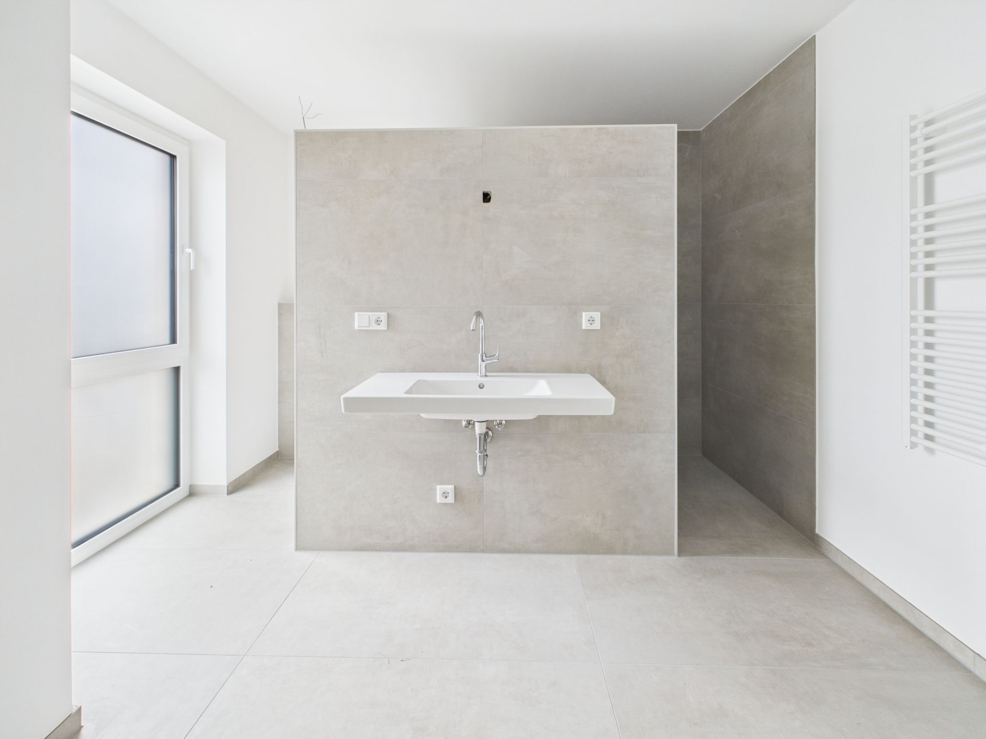 Modernes, helles Badezimmer mit großem Waschbecken und begehbarer Dusche.