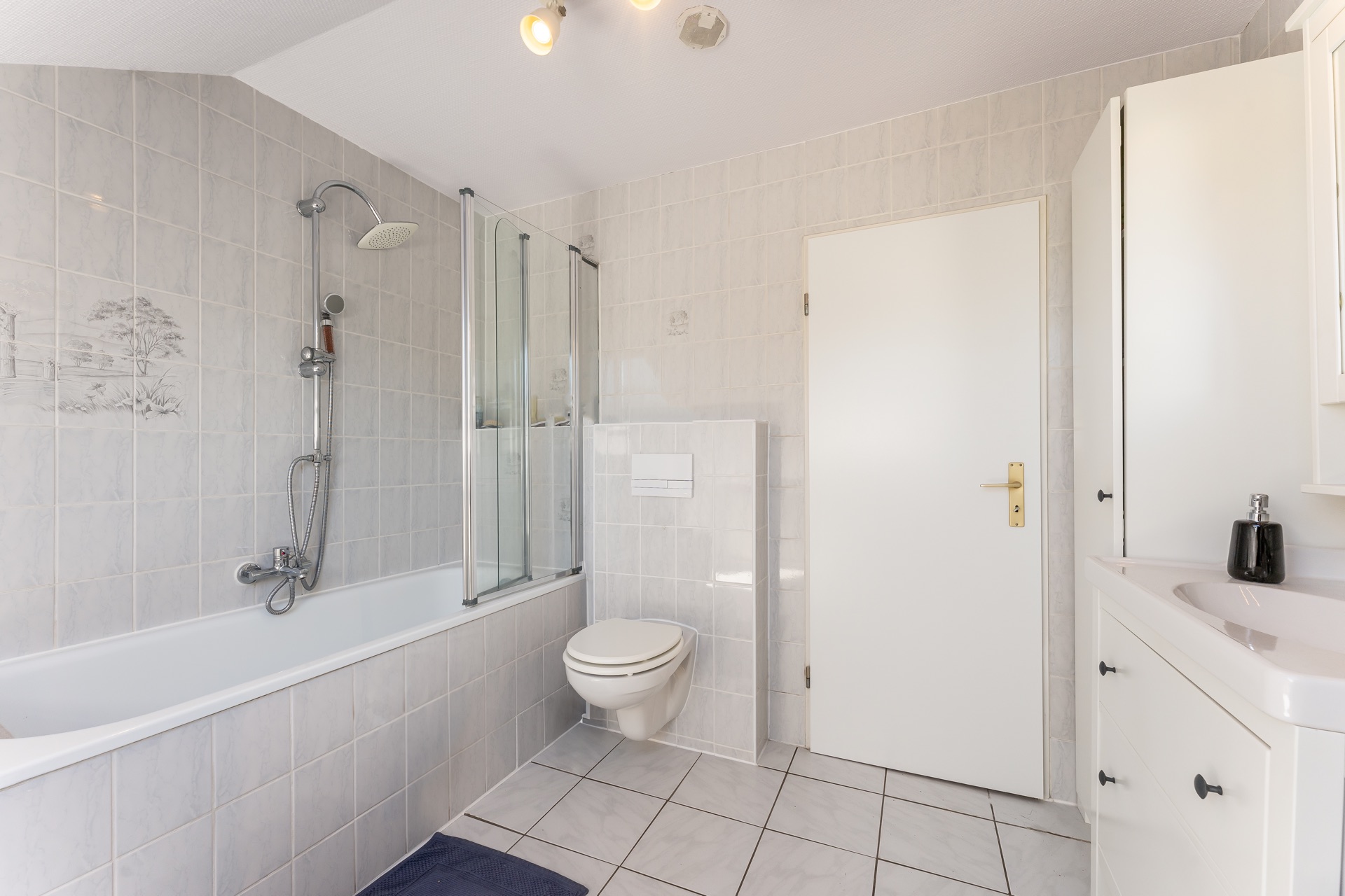 Helles Badezimmer mit Badewanne, Dusche, WC und Waschbecken mit Unterschrank.