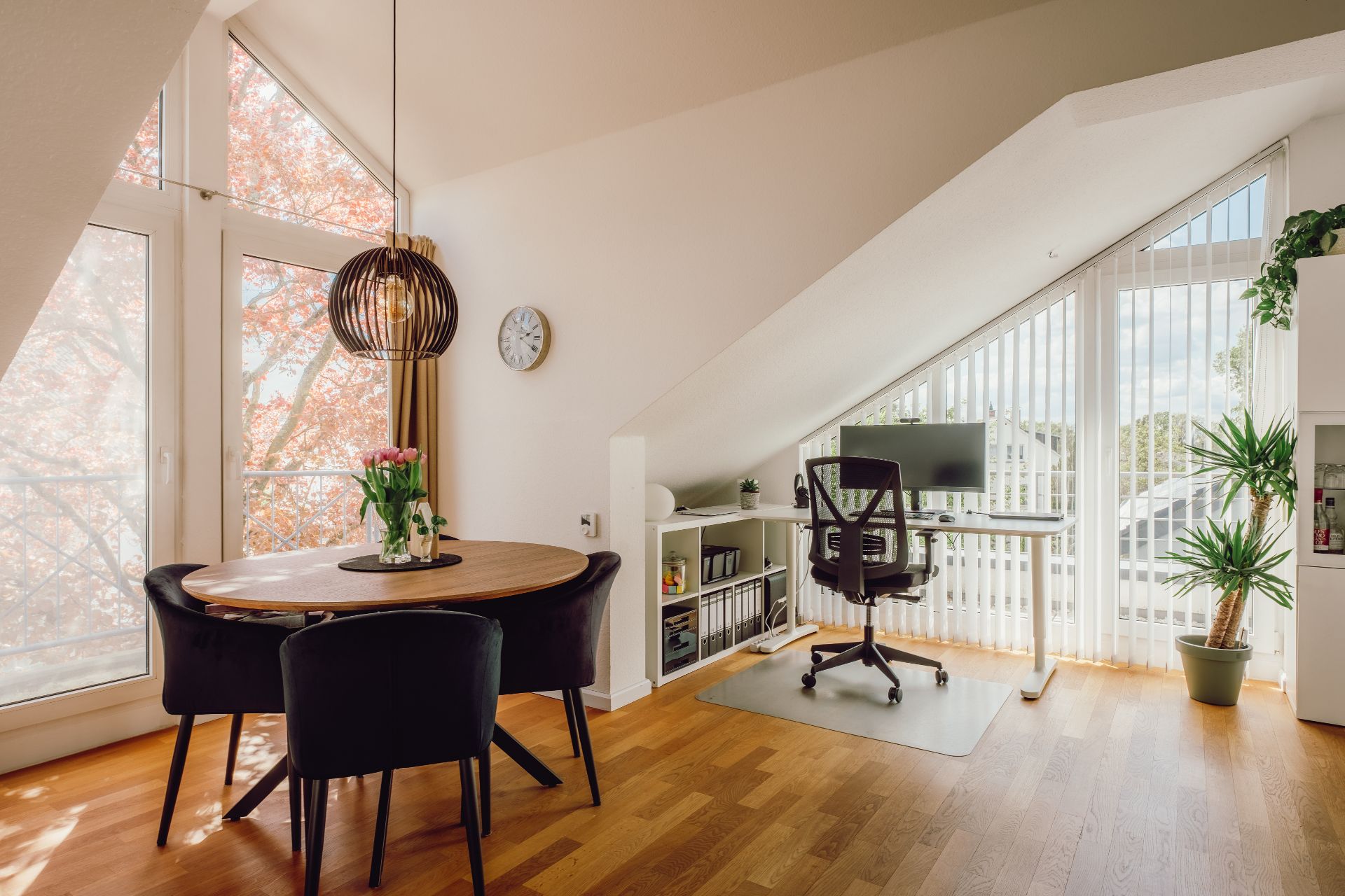 Heller Wohnraum mit Esstisch, Stühlen, Homeoffice-Bereich und großen Fenstern.