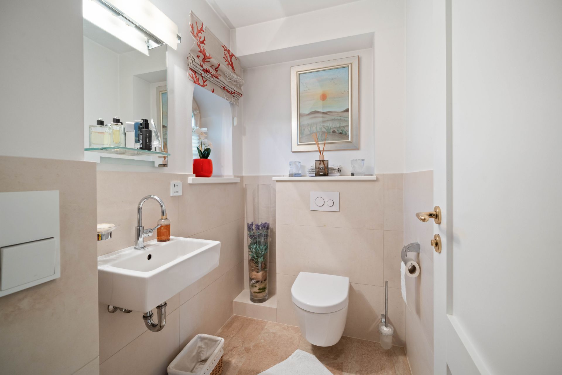 Kleines Badezimmer mit Waschbecken, WC, Spiegel und Dekorationen an der Wand.