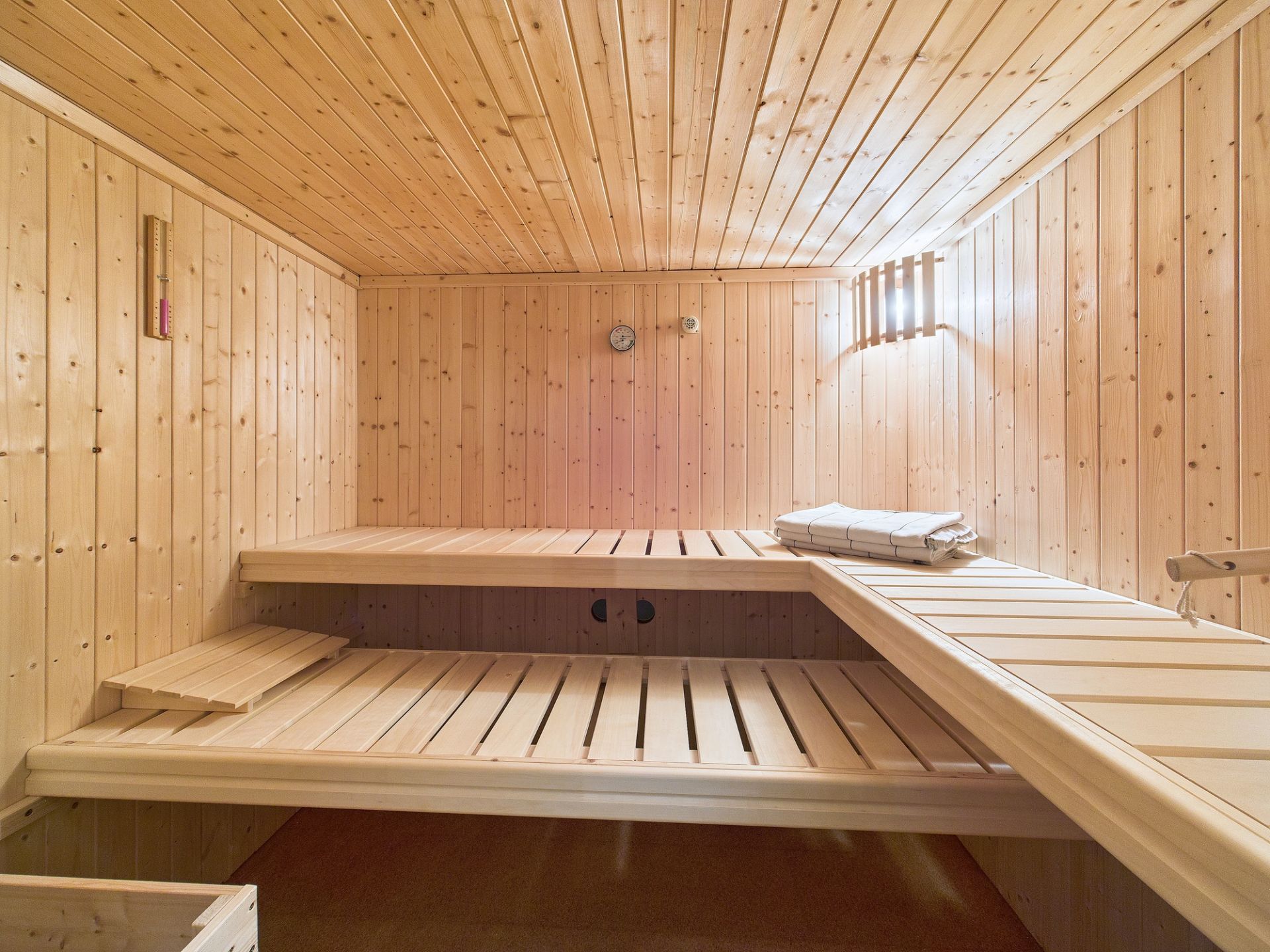 Helle Holzsauna mit zwei Bänken und Handtüchern auf der oberen Bank.